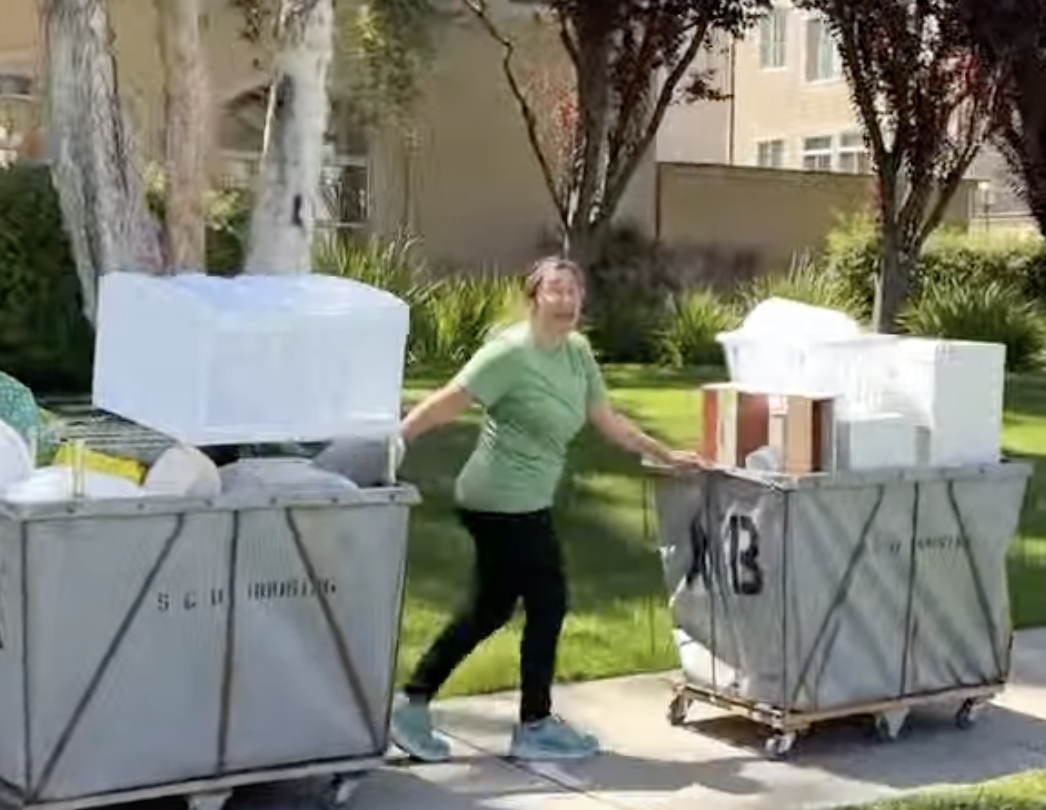 A person moving two rolling carts full of donated items across campus